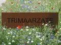 Het naambord van Trimaarzate tussen kleurrijke bloemen