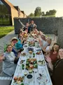 Een groep gasten aan de lange tafel op het terras