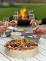 Samen klinken aan de tuintafel met hapjes en een vuurschaal