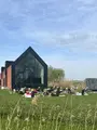 Gasten ontspannen op het gazon voor de glazen gevel