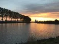 Zonsondergang boven het kanaal met bomen langs de oever