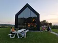 Gasten aan een picknicktafel voor de glazen gevel bij avondlicht