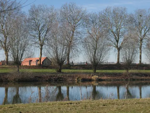 Bomen langs het kanaal met een huis op de achtergrond
