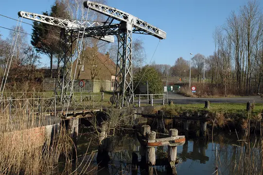 Oude sluis met een metalen hefconstructie tussen het riet