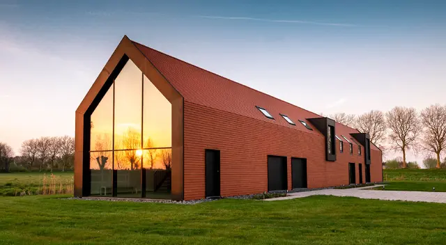Avondzon weerspiegeld in de glazen gevel van Trimaarzate